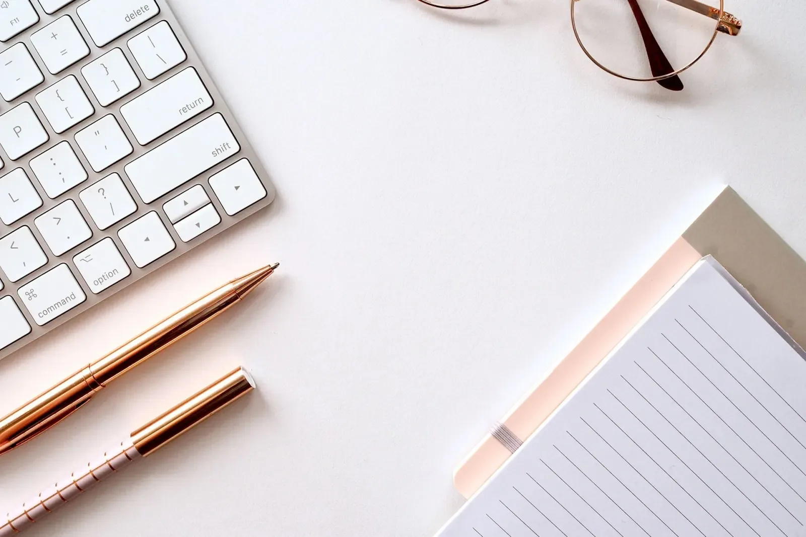 Schreibtisch mit Tastatur, Brille, Stiften und Notizblock